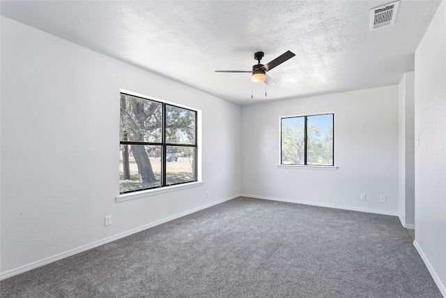 empty room featuring ceiling fan, dark carpet, and a textured ceiling