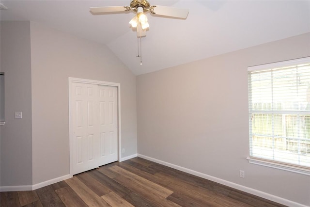 unfurnished bedroom featuring multiple windows, vaulted ceiling, dark hardwood / wood-style floors, and a closet