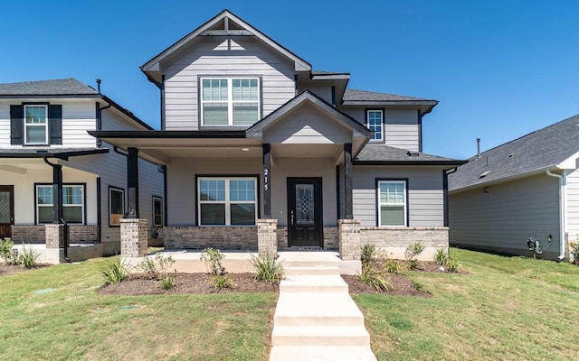 215 Tokalaun Dr, Hutto, TX 78634 - craftsman house with brick siding, a front yard, and covered porch