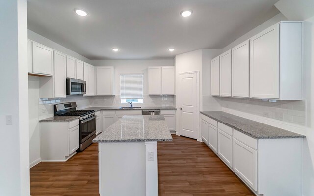 kitchen with a kitchen island, stainless steel appliances, white cabinets, dark wood-type flooring, and sink