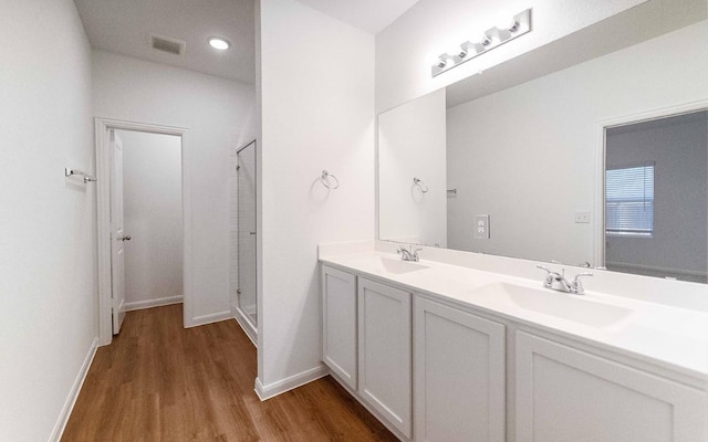 215 Tokalaun Dr, Hutto, TX 78634 - bathroom featuring wood finished floors, a stall shower, double vanity, and recessed lighting