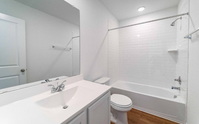 full bathroom with tiled shower / bath combo, hardwood / wood-style floors, vanity, and toilet