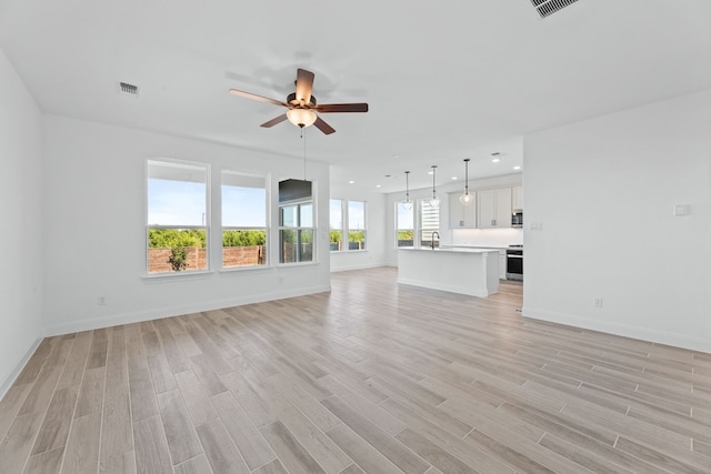 unfurnished living room featuring ceiling fan, light hardwood / wood-style flooring, and sink