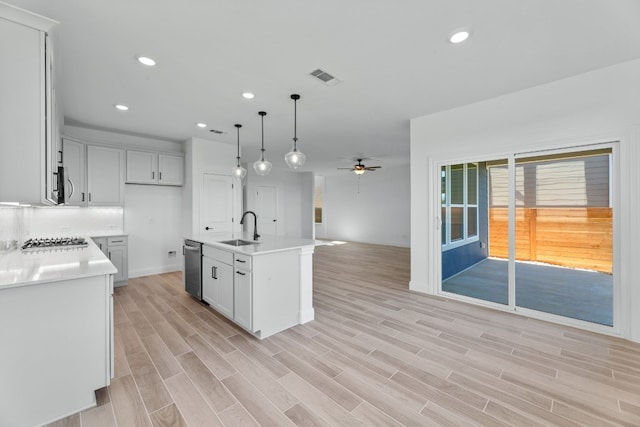 kitchen featuring a center island with sink, sink, ceiling fan, decorative light fixtures, and stainless steel appliances