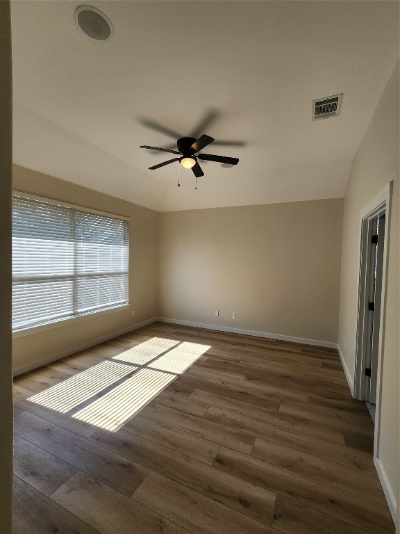 empty room with ceiling fan, dark hardwood / wood-style floors, and vaulted ceiling