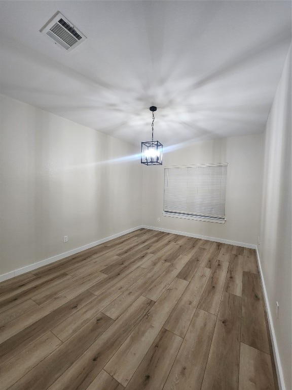 unfurnished room with a chandelier and wood-type flooring