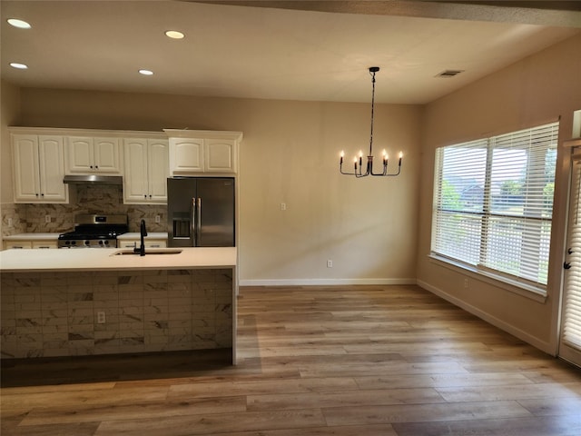 kitchen with light wood-type flooring, tasteful backsplash, stainless steel gas range, black refrigerator with ice dispenser, and white cabinets