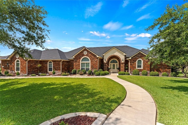 view of front of house featuring brick siding, roof with shingles, and a front yard