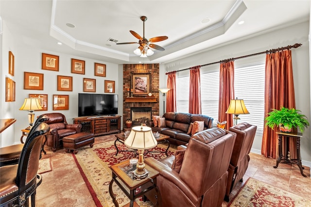 living room with a fireplace, a tray ceiling, ceiling fan, and light tile patterned floors