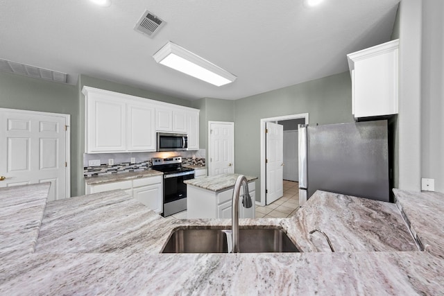 kitchen with sink, stainless steel appliances, white cabinetry, and light tile patterned floors