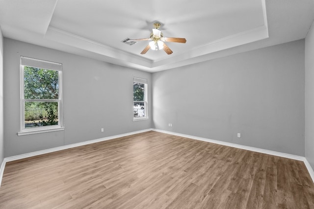 empty room with ceiling fan, hardwood / wood-style floors, and a raised ceiling