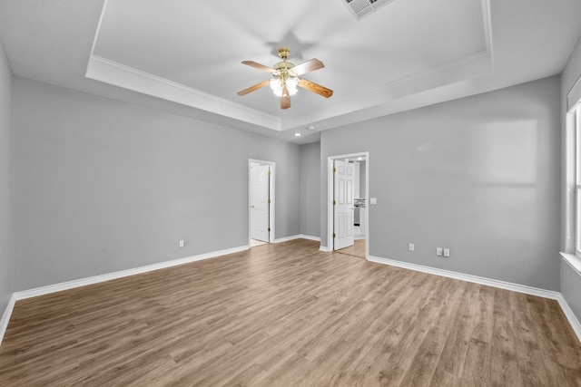 empty room featuring ceiling fan, hardwood / wood-style floors, and a tray ceiling