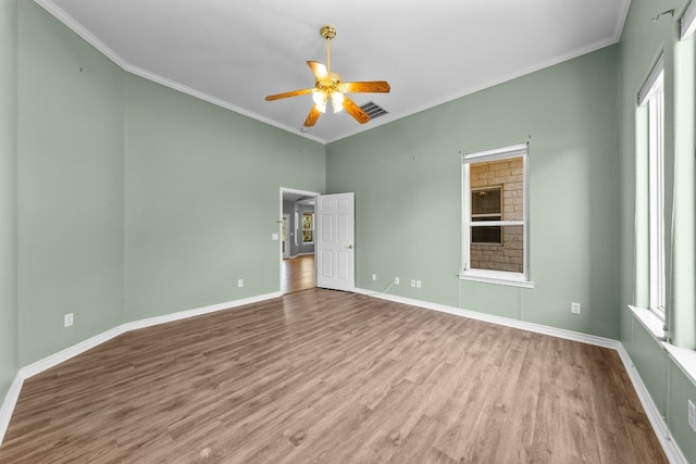 empty room featuring plenty of natural light, ceiling fan, hardwood / wood-style floors, and crown molding