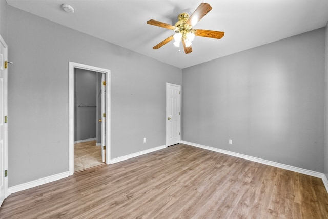 unfurnished bedroom with light wood-type flooring, a spacious closet, ceiling fan, and a closet