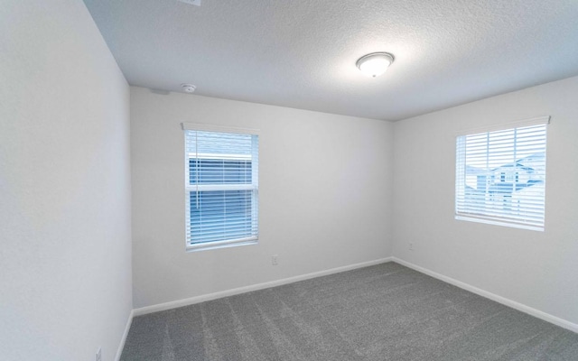 carpeted spare room with a textured ceiling and baseboards