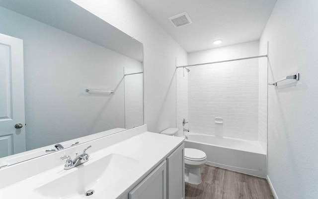 bathroom with shower / washtub combination, visible vents, toilet, vanity, and wood finished floors