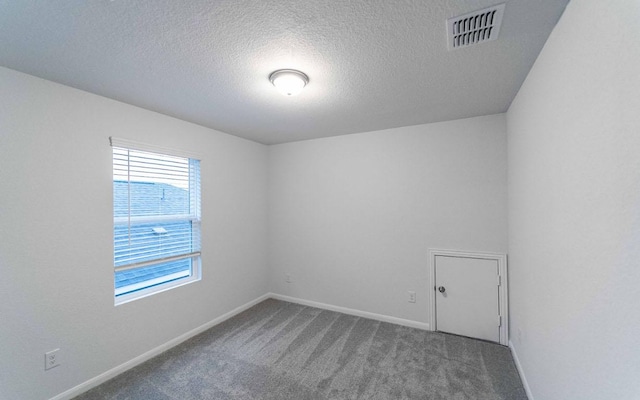 carpeted empty room with visible vents, a textured ceiling, and baseboards