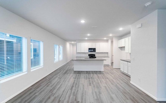 kitchen with baseboards, white cabinets, stove, light wood-style floors, and black microwave