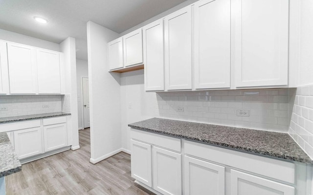 kitchen featuring light wood finished floors, white cabinets, and dark stone countertops