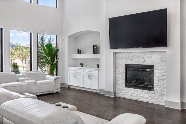 living room with a fireplace, a healthy amount of sunlight, dark hardwood / wood-style floors, and a high ceiling