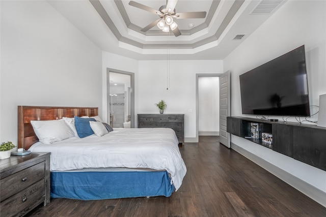 bedroom featuring ceiling fan, dark wood-type flooring, a tray ceiling, and ensuite bath