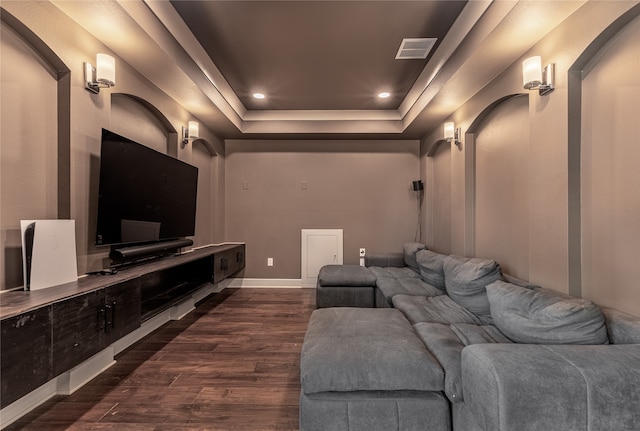 home theater room featuring a raised ceiling and dark hardwood / wood-style floors