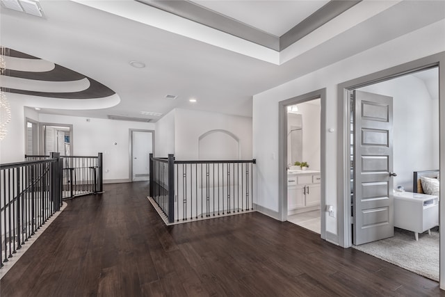 corridor with dark hardwood / wood-style floors and a raised ceiling