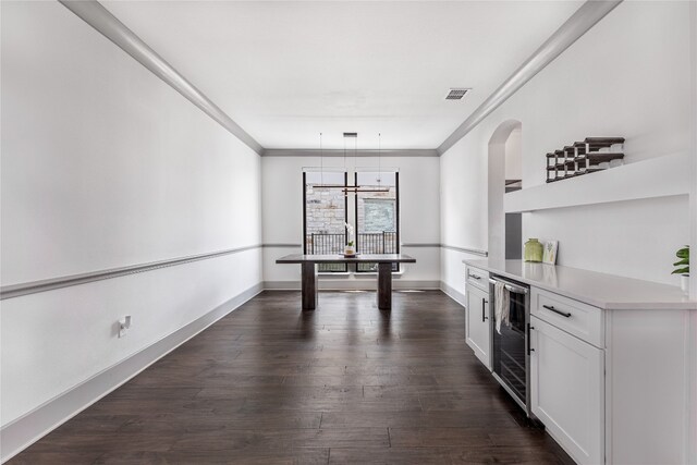 interior space with white cabinets, beverage cooler, hanging light fixtures, dark hardwood / wood-style floors, and ornamental molding