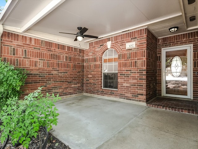 view of exterior entry with ceiling fan and a patio area