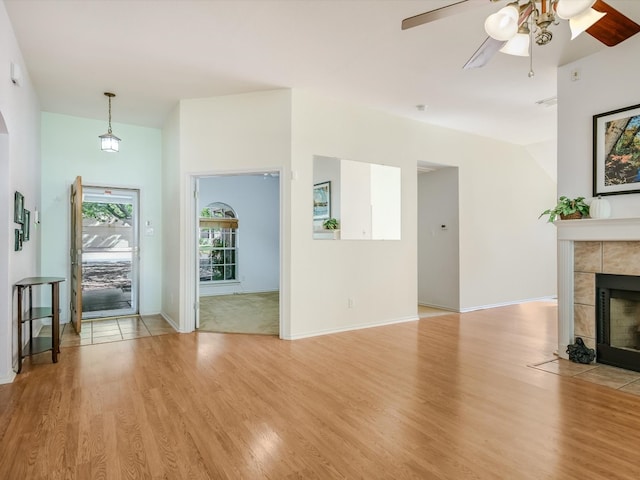 living room with ceiling fan, light hardwood / wood-style flooring, and a tile fireplace