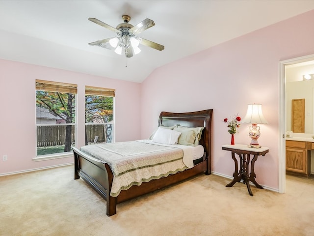 bedroom with ceiling fan, light carpet, and ensuite bathroom