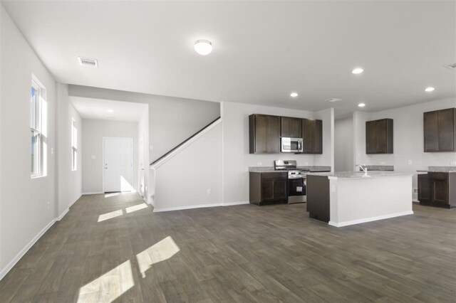 kitchen with dark wood-type flooring, an island with sink, stainless steel appliances, and dark brown cabinets