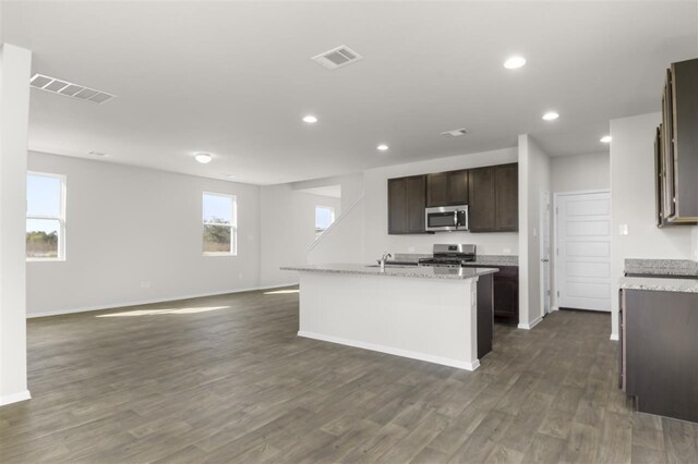 kitchen featuring a kitchen island with sink, sink, dark hardwood / wood-style floors, appliances with stainless steel finishes, and dark brown cabinets