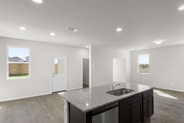 kitchen featuring hardwood / wood-style floors, light stone countertops, sink, and stainless steel dishwasher