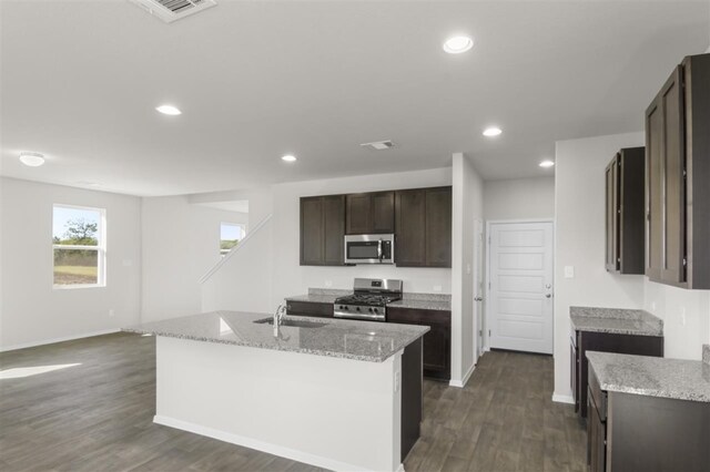 kitchen with dark hardwood / wood-style flooring, a kitchen island with sink, sink, and appliances with stainless steel finishes