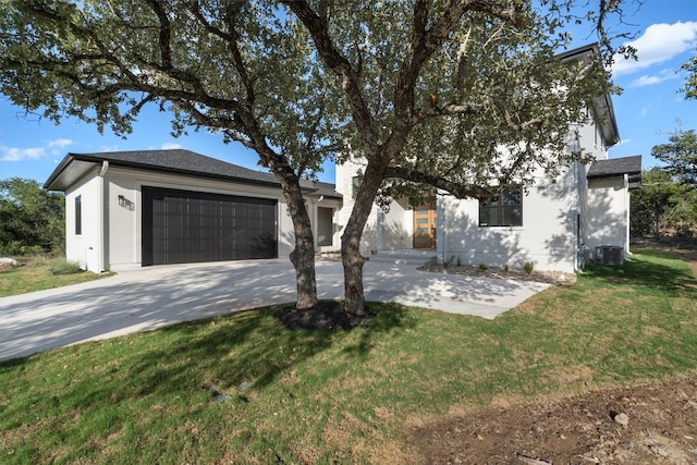 view of front of property with a garage, a front yard, and central AC