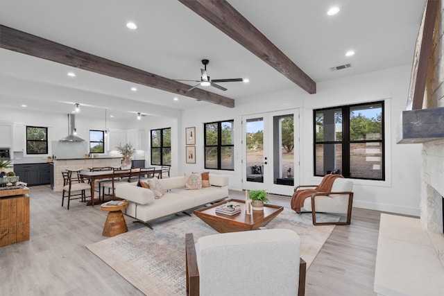 living room with a wealth of natural light, french doors, beamed ceiling, and light hardwood / wood-style floors