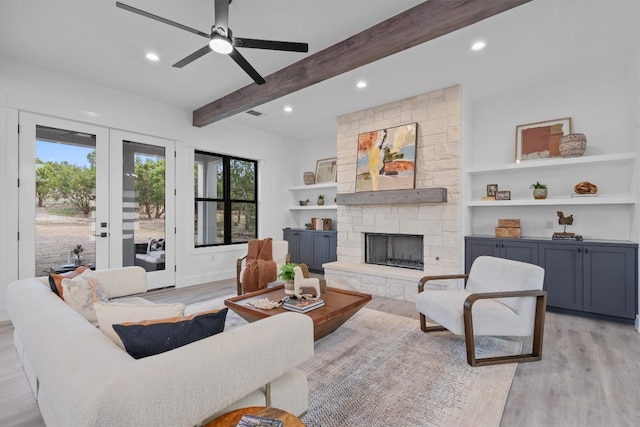 living room with ceiling fan, french doors, beamed ceiling, a fireplace, and light wood-type flooring