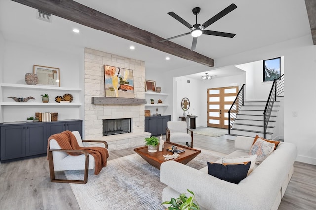 living room featuring a fireplace, ceiling fan, light hardwood / wood-style flooring, and beamed ceiling