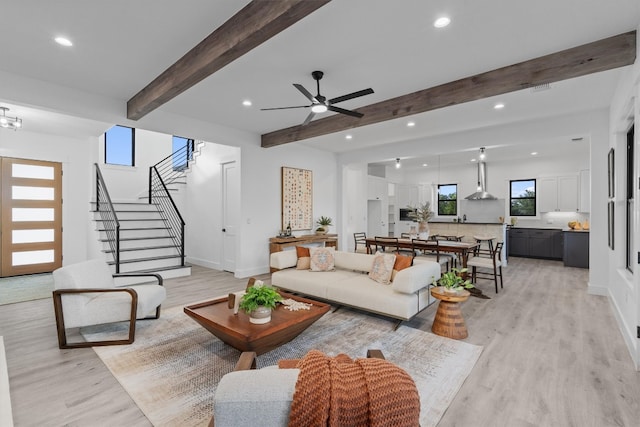 living room featuring beam ceiling, ceiling fan, plenty of natural light, and light hardwood / wood-style floors