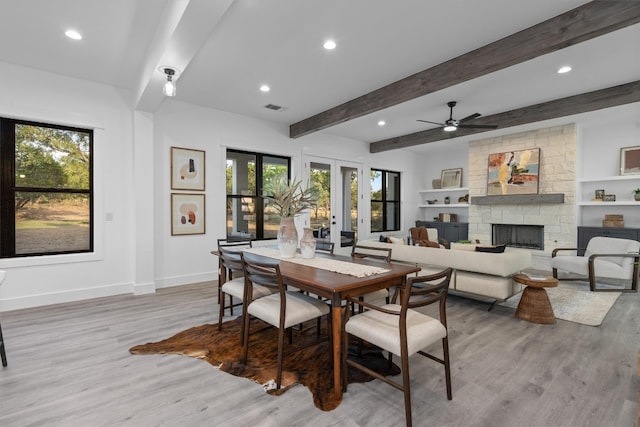 dining room featuring a wealth of natural light, a fireplace, french doors, and light wood-type flooring