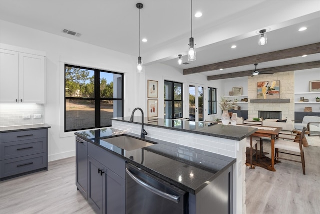 kitchen with white cabinets, a healthy amount of sunlight, sink, and an island with sink