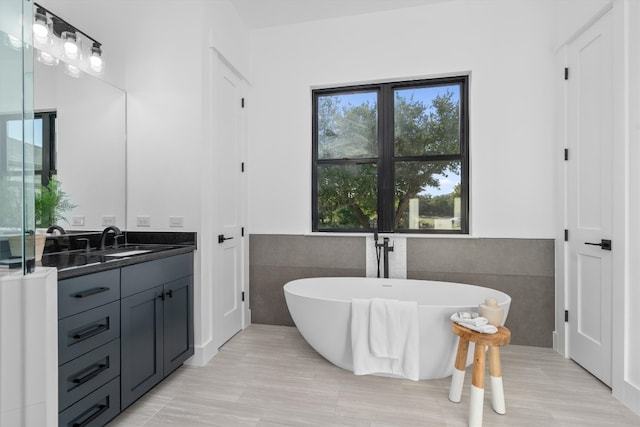 bathroom featuring a bathing tub, vanity, and tile walls