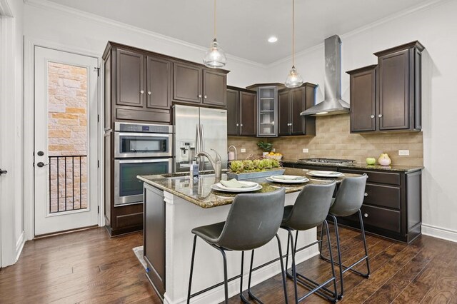 kitchen featuring appliances with stainless steel finishes, wall chimney exhaust hood, decorative backsplash, stone countertops, and dark hardwood / wood-style floors