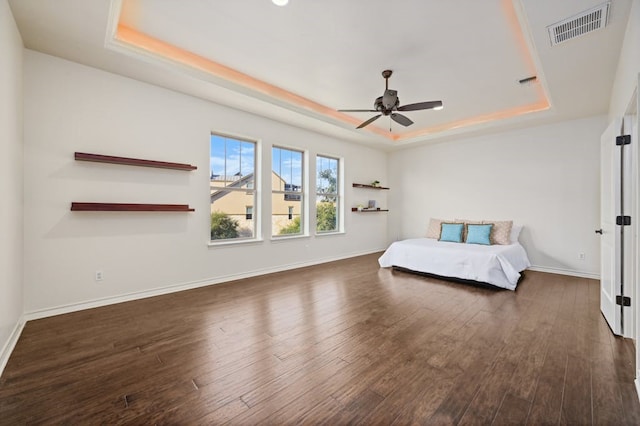 unfurnished bedroom featuring ceiling fan, dark hardwood / wood-style floors, and a tray ceiling