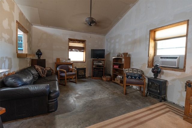 living room featuring plenty of natural light, lofted ceiling, concrete floors, and a wood stove