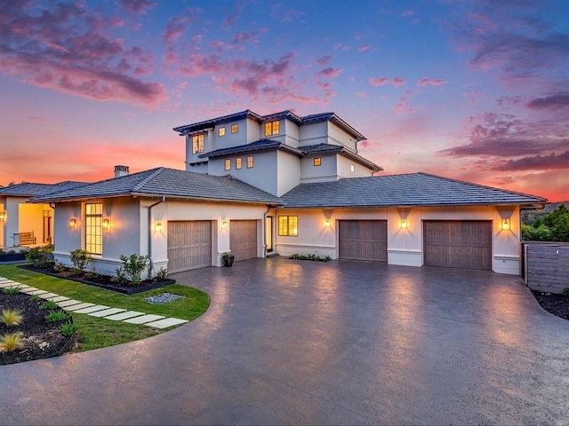 prairie-style house with a tile roof, driveway, a chimney, and an attached garage