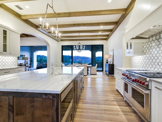 kitchen featuring a chandelier, range with two ovens, glass insert cabinets, and white cabinetry