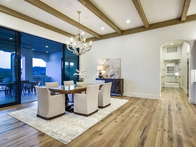 dining space featuring arched walkways, visible vents, baseboards, light wood-type flooring, and an inviting chandelier