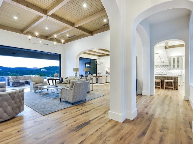 living room with beam ceiling, light wood-type flooring, a mountain view, and a notable chandelier